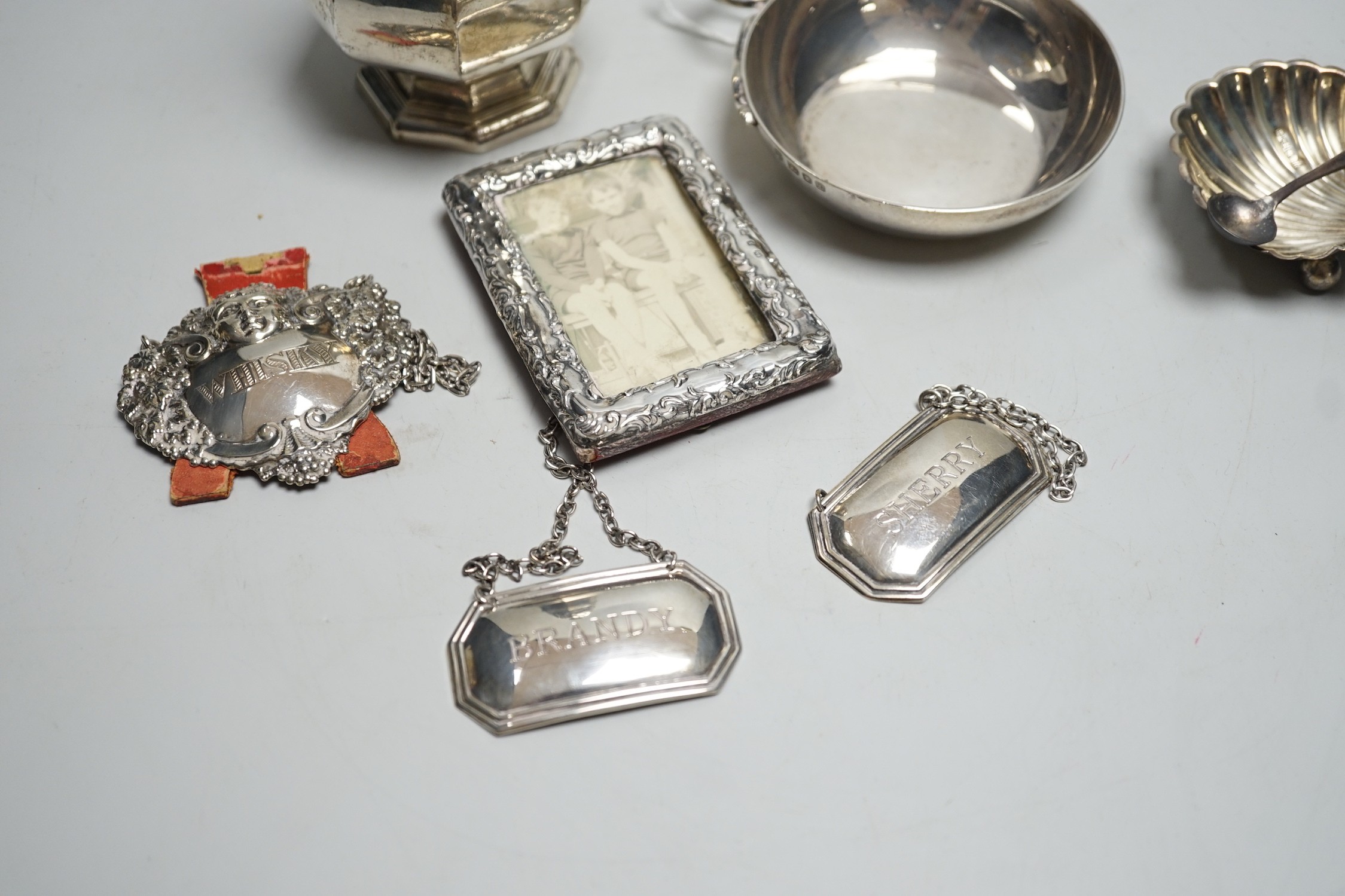 A George V silver octagonal baluster sugar caster, by Walker & Hall, 16.4cm, a modern silver taste du vin, three modern silver wine labels, a silver shell salt, silver condiment spoon and a late Victorian miniature silve